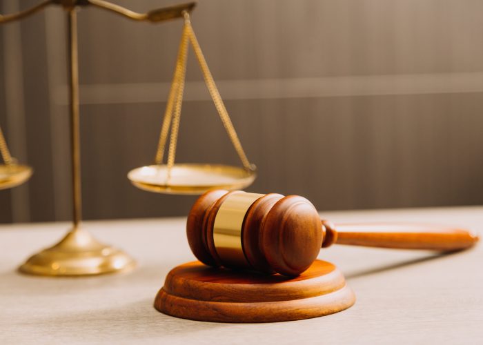 Business and lawyers discussing contract papers with brass scale on desk in office. Law, legal services, advice, justice and law concept picture with film grain effect